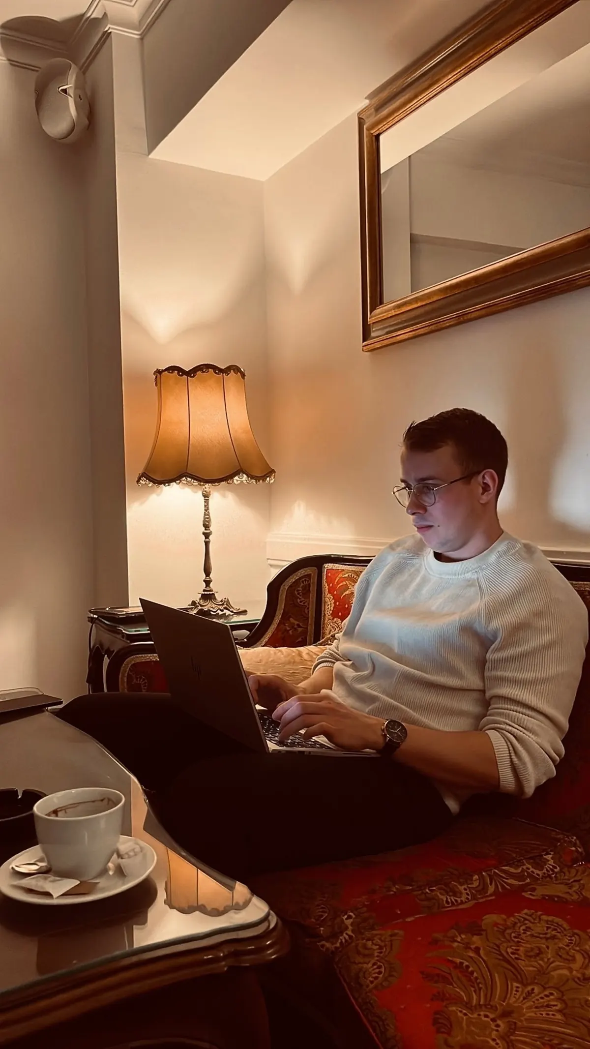 Christopher Krassnig in an armchair by a lamp, a laptop on his lap