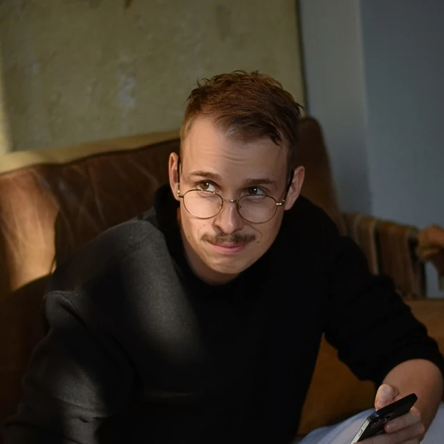 Christopher Krassnig on a leather sofa, phone in hand